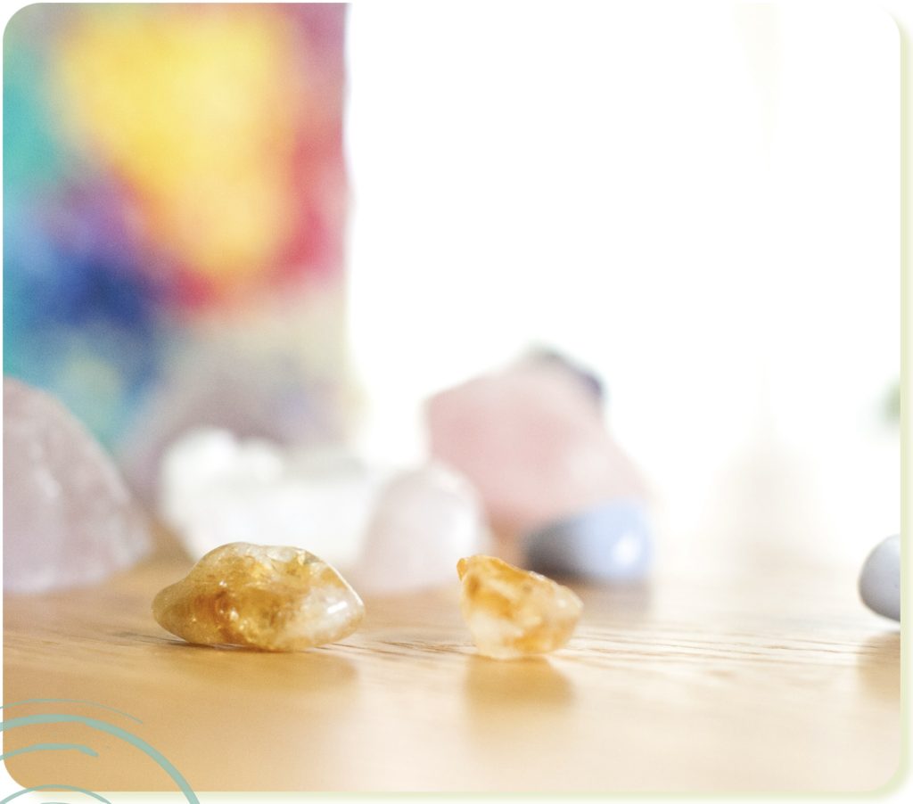 Photograph of crystals in soft focus on wood table with colour and light background, to inspire entrepreneurs to gather their inspiration