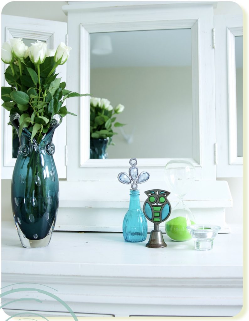 White roses in green glass vase in front of mirror with green decorative elements in home decor, image by Vig Gleeson Irish personal brand photographer copyright